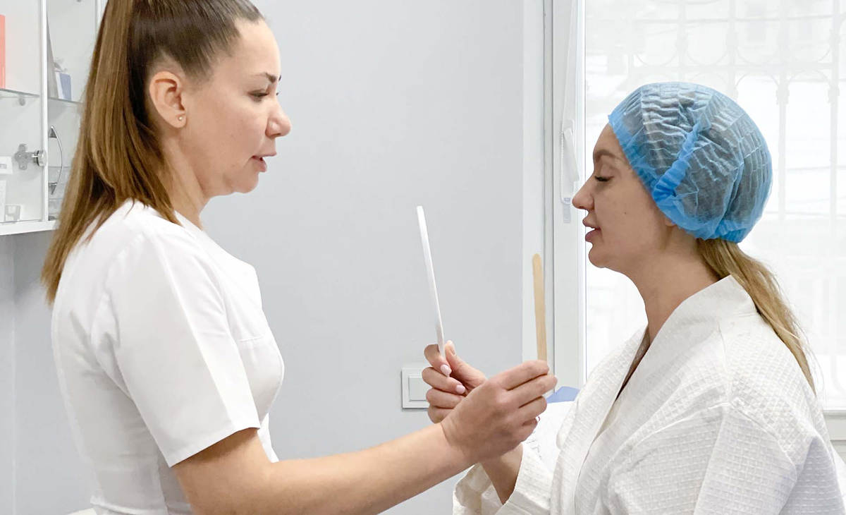 Лікар показує результати збільшення губ пацієнту в дзеркалі